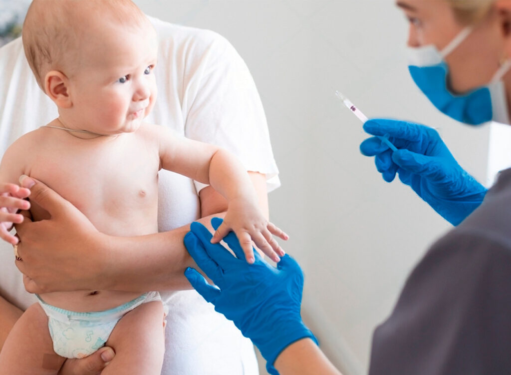 Médico sosteniendo una vacuna, qué es la de tosferina, para administrarsela un paciente pediátrico en brazos de su papá.